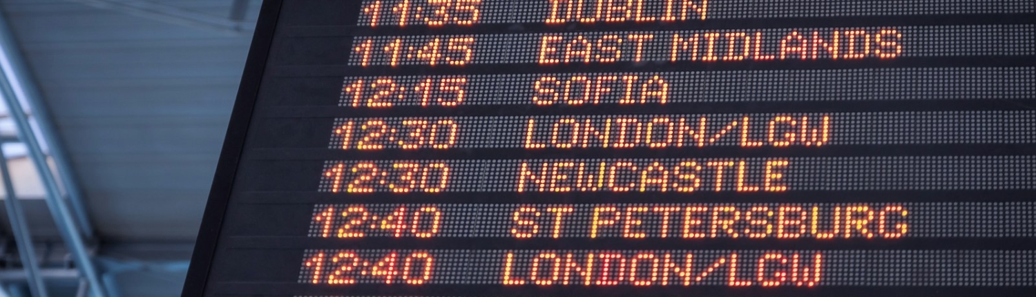 A low-angle shot of a departure board at an airport