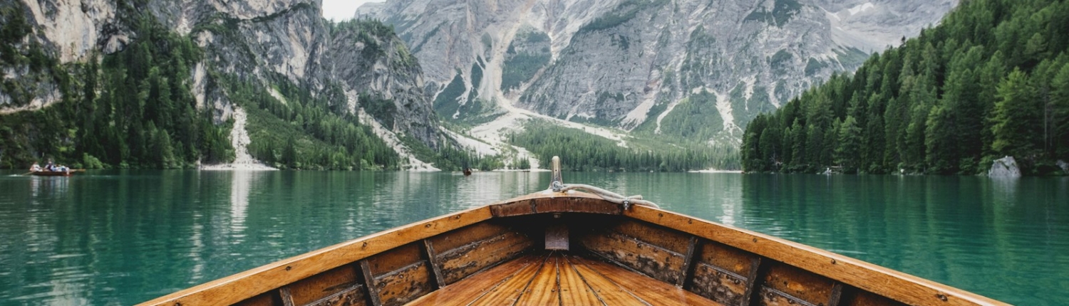 brown wooden boat moving towards the mountain