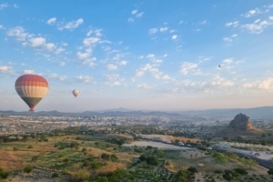 two hot air balloons flying over a city