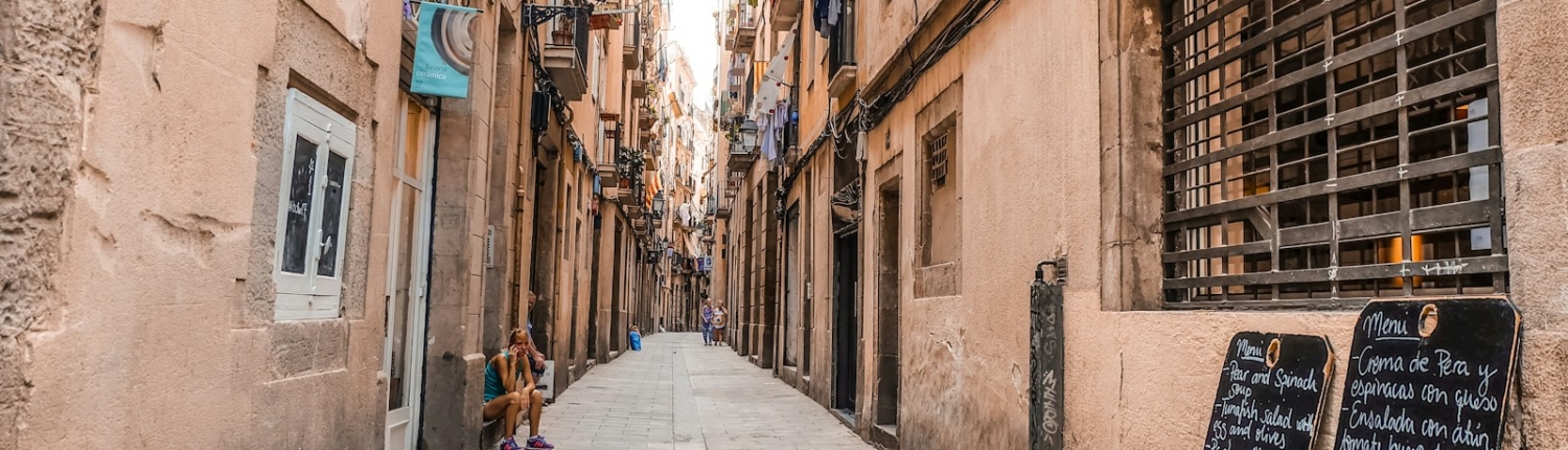 a narrow city street with a sidewalk lined with buildings